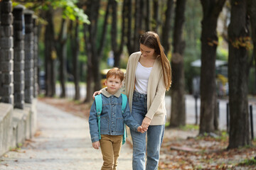 Fototapeta premium Young mom taking her son to school