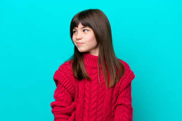 Little caucasian girl isolated on blue background making doubts gesture looking side