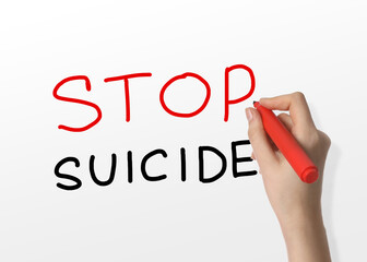 Woman writing phrase Stop Suicide on whiteboard, closeup