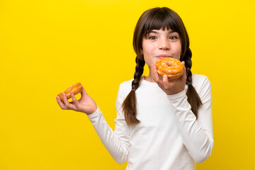 Little caucasian girl isolated on yellow background holding a donut