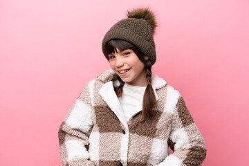 Little caucasian girl with winter jacket isolated on pink background laughing