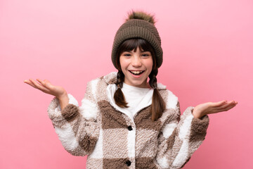 Little caucasian girl with winter jacket isolated on pink background with shocked facial expression