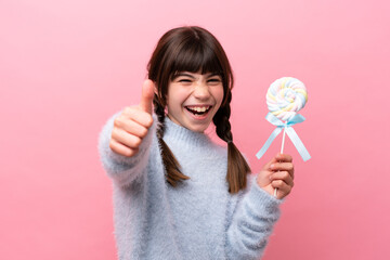 Little caucasian girl holding a lollipop with thumbs up because something good has happened