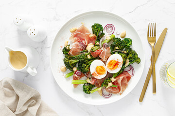 Easter egg salad with prosciutto and broccolini on white background, top view. Easter salad with...