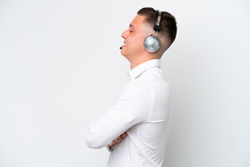 Telemarketer Brazilian man working with a headset isolated on white background in lateral position
