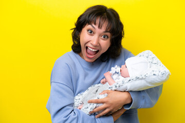 Young Argentinian woman with her cute baby isolated on yellow background