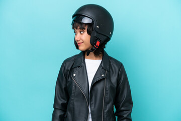 Young Argentinian woman with a motorcycle helmet isolated on blue background looking to the side