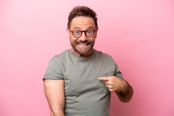 Middle age man wearing a band aids isolated on pink background with surprise facial expression