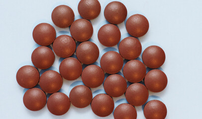 Brown dietary supplement pills on a blue background.