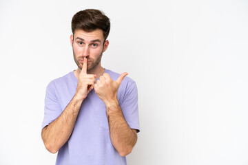 Young caucasian man isolated on white background pointing to the side and doing silence gesture