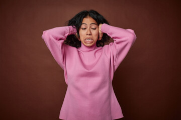 Young colombian curly hair woman isolated on brown background screaming with rage.