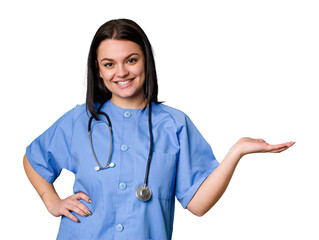 Young nurse woman isolated showing a copy space on a palm and holding another hand on waist.