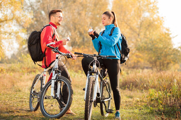 Beautiful young Caucasian couple eating energy bars and talking while taking a break from a...