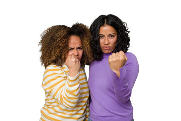 Two female friends isolated in studio showing fist to camera, aggressive facial expression.