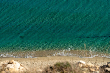 Clear windy sea and an empty beach with footprints in the sand view from the cliff. A mindfulness place of silence and unity with nature concept.