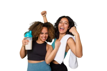  Two best friends are ready to go to the gym, one of them holds a protein shake, raising fist after a victory, winner concept. © Asier