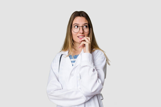 Compassionate female physician with a stethoscope around her neck, ready to diagnose and care for her patients in her signature white coat relaxed thinking about something looking at a copy space.