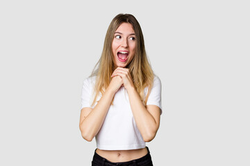 Young blonde posing for a portrait isolated, exuding natural beauty and radiance keeps hands under...
