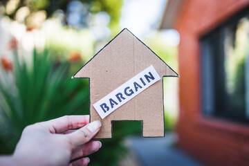 finding a dream property and real estate market affordability, Bargain label on cardboard house in...