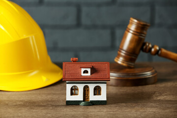 Construction and land law concepts. House model, gavel and hard hat on wooden table, closeup