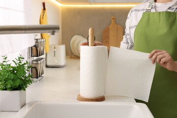 Woman using paper towels in kitchen, closeup