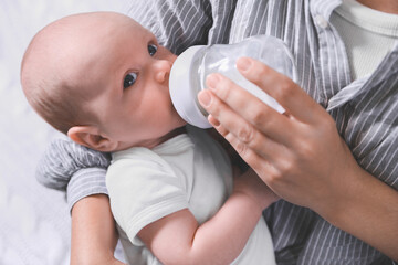 Mother feeding her little baby from bottle, closeup