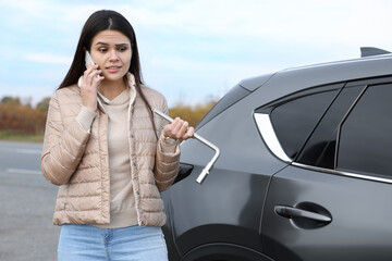 Worried young woman calling car service. Tire puncture