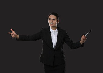 Happy young conductor with baton on dark background