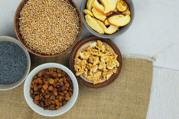 Wheat, raisins, poppy seeds, walnuts, dried apples. Ingredients for Ukrainian kutia in bowls. Copy space. Top view.