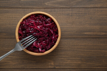 Obraz na płótnie Canvas Tasty red cabbage sauerkraut on wooden table, top view. Space for text