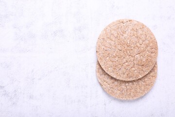 Tasty crispbreads on white textured table, top view. Space for text