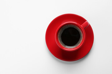 Red cup with aromatic coffee on white background, top view. Space for text