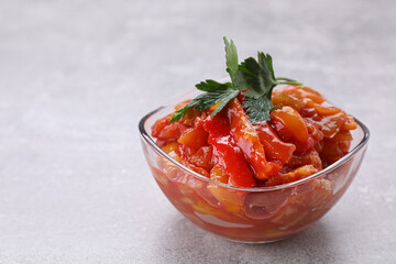 Delicious lecho with parsley in glass bowl on light gray table