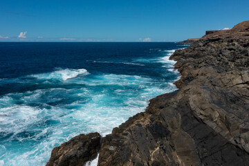Beautiful landscape with deep blue water. Powerful waves crash against black volcanic rocks on the coast of ´Aguas Verdes, Fuerteventura island. Selective focus, blurred background.
