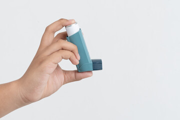 Asian boy hand holding asthma inhaler on white background with space for text