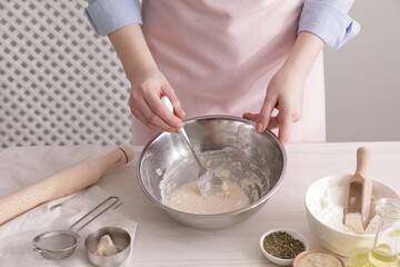 Woman making traditional grissini at white wooden table indoors, closeup