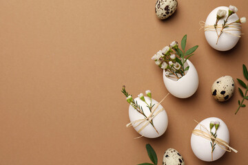 Fototapeta na wymiar Happy Easter. Festive composition with eggs and floral decor on brown background, flat lay. Space for text.