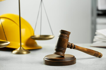 Construction and land law concepts. Gavel, scales of justice and hard hat on white table indoors, closeup