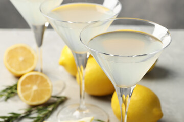 Martini glasses of refreshing cocktail, lemon and rosemary on light grey table, closeup