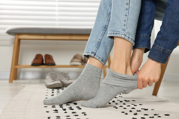 Woman putting on grey socks at home, closeup