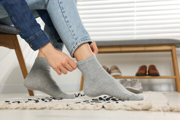 Woman putting on grey socks at home, closeup
