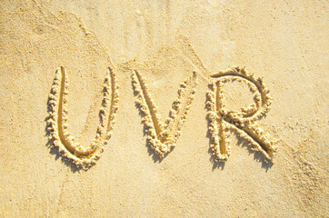 Three letters UVR are written on sand, representing ultraviolet radiation.