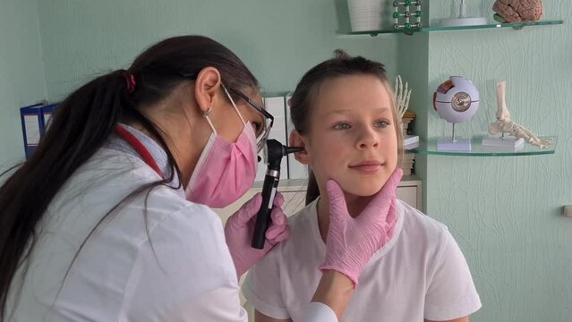 Otorhinolaryngologist examines little girl ear with otoscope. Adenoiditis as cause of otitis media in children