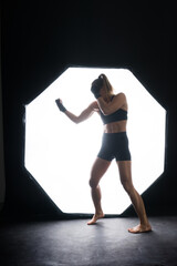 Fototapeta na wymiar Cool female fighter in boxing bandages trains in studio. Mixed martial arts.
