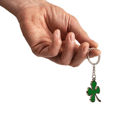 Hand holding shamrock, leaf shaped trinket, key ring isolated on white background