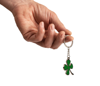 Hand holding shamrock, leaf shaped trinket, key ring isolated on white background