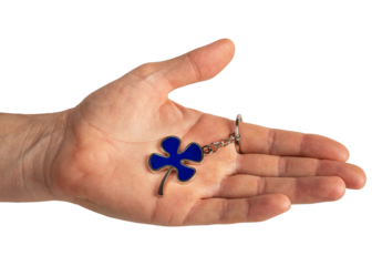 Hand holding shamrock, blue leaf shaped trinket isolated on white background