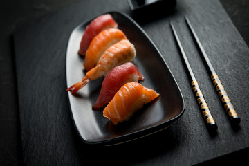 sushi with chopstick over black stone