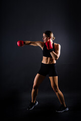 Cool female fighter in boxing bandages trains in studio. Mixed martial arts.