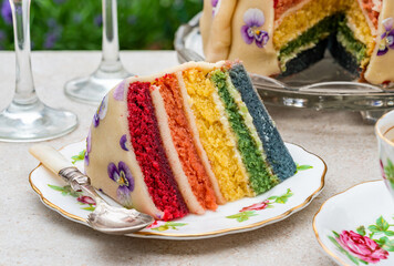 Multi layered rainbow cake set on garden table - outdoor dining